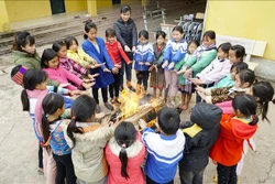 Cô và trò Trường Phổ thông Dân tộc Bán trú Tiểu học Leng Su Sìn (huyện Mường Nhé) đốt lửa sưởi ấm. Ảnh: Xuân Tư – TTXVN