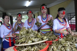 Các cô gái dân tộc Cor với những chiếc bánh lá đót trong Tết Ngã rạ. Ảnh: Đinh Hương – TTXVN 
