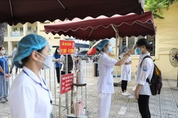 Thí sinh được đo kiểm tra thân nhiệt, sát khuẩn tay trước khi vào điểm thi THPT Nguyễn Gia Thiều (quận Long Biên, Hà Nội). Ảnh: Minh Quyết - TTXVN