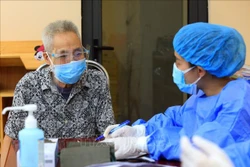 Ông Trịnh Xuân Nghĩa (77 tuổi), phường Trung Hòa, quận Cầu Giấy được nhân viên y tế tư vấn trước khi tiêm vaccine phòng COVID-19 . Ảnh: Tuấn Anh - TTXVN
