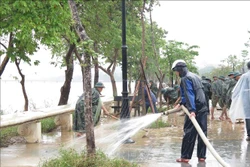 Các lực lượng dọn dẹp bùn đất tại khu vực 2 bên bờ sông Hương. Ảnh: Tường Vi - TTXVN
