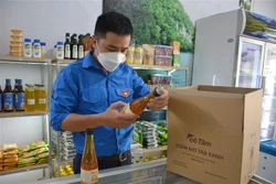 Anh Vũ Minh Ngọc kiểm tra giấm mơ trà xanh trước khi giao cho khách hàng. Ảnh: Công Luật - TTXVN 