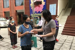 Chủ tịch Hội Liên hiệp phụ nữ thành phố Hà Nội Lê Kim Anh trao suất quà cho nữ lao động di cư gặp khó khăn. Ảnh: TTXVN phát 