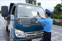 Lực lượng chức năng quét mã QR của phương tiện tham gia giao thông tại chốt kiểm soát dịch ngã 3 Cầu Giẽ, huyện Phú Xuyên hướng từ Hà Nam về Hà Nội trên tuyến Quốc lộ 1A. Ảnh: Phạm Kiên - TTXVN 
