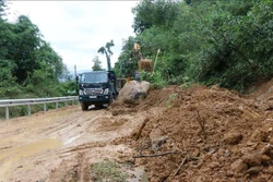 Khẩn trương dọn bùn, đất để người dân lưu thông trên đường tỉnh lộ 622B. Ảnh: Sỹ Thắng - TTXVN 
