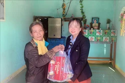 Bí thư Đảng ủy Khánh Trung Cao Thị Ngọc Thanh trao tặng quà tết cho các hộ gia đình chính sách. Ảnh: Phan Sáu - TTXVN