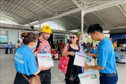 Các du khách nước ngoài rất ủng hộ việc làm của huyện đảo Cô Tô, vui vẻ thay đổi túi nilon sang túi giấy. Ảnh: TTXVN