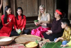 Thí sinh Hoa hậu Du lịch thế giới năm 2022 trải nghiệm gói bánh chưng tại làng cổ Hùng Lô, xã Hùng Lô, thành phố Việt Trì (Phú Thọ) - điểm đến được Hội đồng đánh giá, phân hạng Chương trình Mỗi xã một sản phẩm (OCOP) Phú Thọ đánh giá là sản phẩm du lịch c