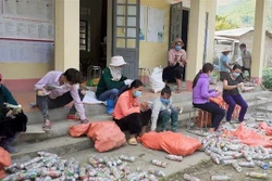 Thành viên Câu lạc bộ “Vệ sinh môi trường” và bà con bản Lun 1, xã Tà Mung, huyện Than Uyên (Lai Châu) làm gạch sinh thái xây dựng tường bao, cổng chào nhà văn hóa của bản. Ảnh: Việt Hoàng-TTXVN 