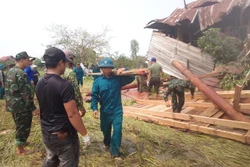 Các lực lượng chức năng hỗ trợ người dân khắc phục thiệt hại do mưa dông, lốc. Ảnh: TTXVN phát