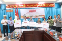5 hộ gia đình chính sách có hoàn cảnh khó khăn về nhà ở nhận bảng tượng trưng trao kinh phí xây nhà. Ảnh: Huỳnh Phúc Hậu - TTXVN