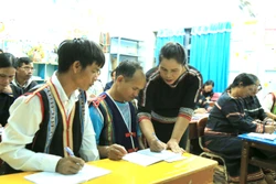 Cô giáo Kso H'Vớt đang chăm chú uốn nắn từng nét chữ cho các học viên. Ảnh: Quang Thái- TTXVN
