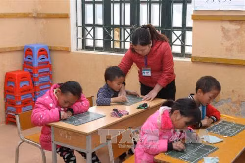 Giáo viên hướng dẫn học sinh tập viết trong giờ học môn Tiếng Việt dạy ở Trường Tiểu học Vừ A Dính, xã Dào San, huyện Phong Thổ (Lai Châu). Ảnh: Quý Trung – TTXVN