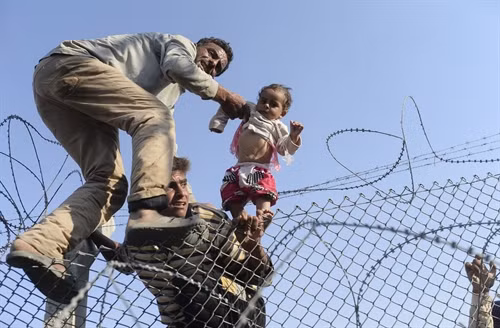 Người di cư Syria cố vượt qua hàng rào dây thép gai để vào Thổ Nhĩ Kỳ ngày 14/6/2015. Ảnh: AFP/TTXVN