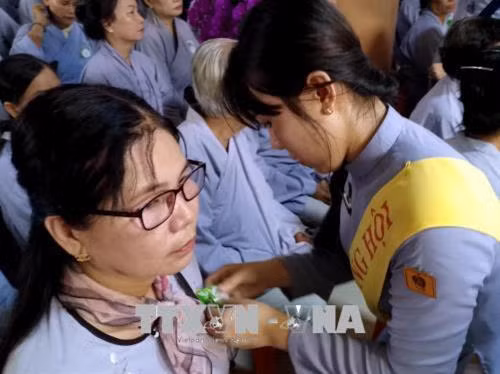 Các Phật tử thực hành Nghi thức "Bông hồng cài áo" trong Vu lan báo hiếu, tại chùa Phật Tổ (phường 4, thành phố Cà Mau). Ảnh: Kim Há - TTXVN