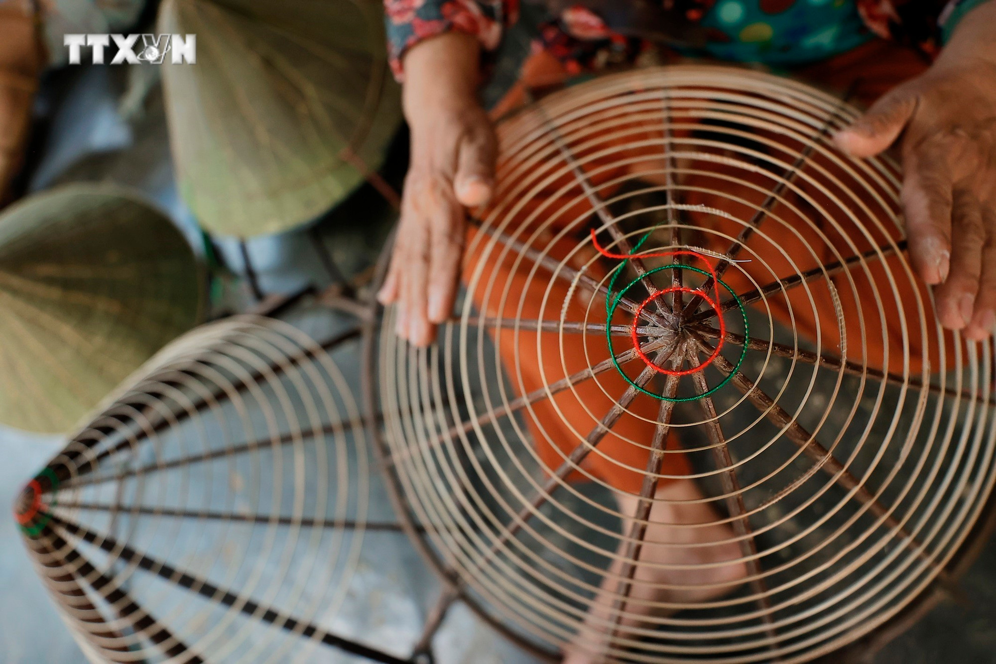 Người thợ chằm nón Làng nón Đốc Sơ (P.Hương Sơ, TP Huế) chuẩn bị nan tre được vót nhỏ uốn quanh khung hình chóp trước khi khâu chằm nón. Ảnh: Minh Quyết - TTXVN vna_potal_du_lich_viet_nam_non_la_sen_san_pham_doc_dao_xu_hue_7540412.jpg
