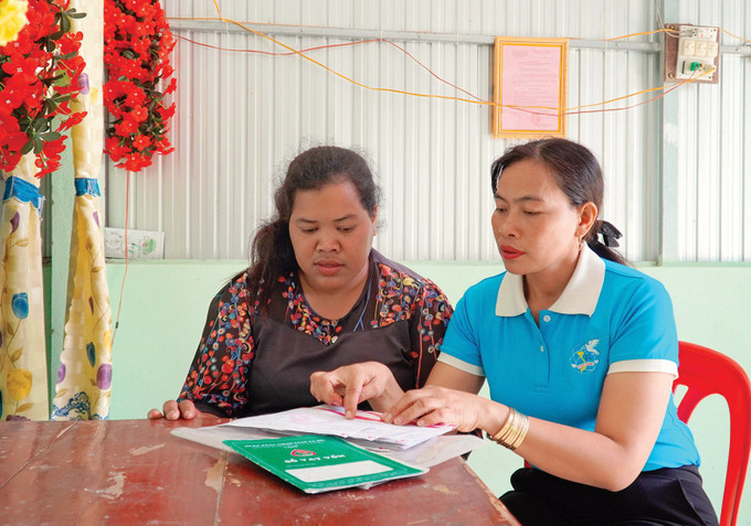 Phó Bí thư Chi bộ ấp Tà Teng Thị Vi hướng dẫn thủ tục thanh toán và vay vốn Ngân hàng Chính sách xã hội cho bà Thị Ngọc Mai (bên trái) ở xã Phú Lợi, huyện Giang Thành (Kiên Giang). Ảnh: Văn Sĩ dong-bao-khmer-kien-giang-voi-niem-vui-an-cu-lac-nghiep-7.jpg