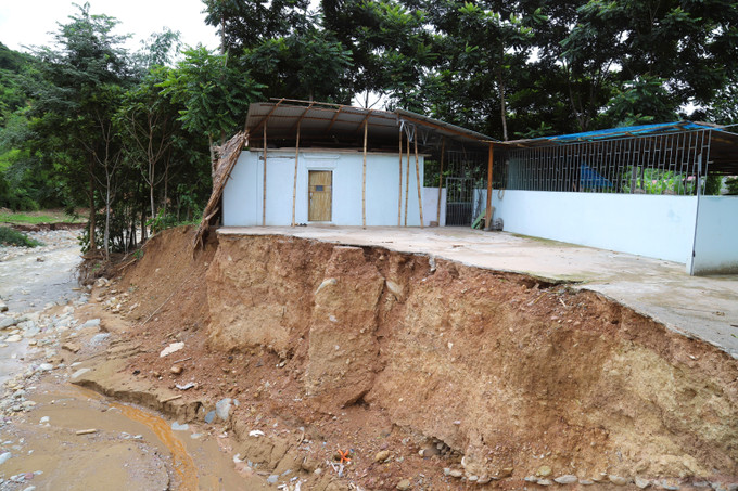 Lũ ống, lũ quét gây sạt lở nghiêm trọng, làm biến dạng bờ suối và cuốn trôi hoàn toàn một ngôi nhà tại bản Huổi Xá (xã Nhôn Mai, tỉnh Nghệ An); phần còn lại của ngôi nhà “treo” bên vách sạt lở. Ảnh: Xuân Tiến/ TTXVN