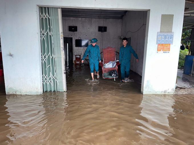 Lực lượng dân quân hỗ trợ người dân di chuyển đồ đạc khỏi vùng ngập lụt ven sông Krông Nô, tỉnh Lâm Đồng. Ảnh: TTXVN phát