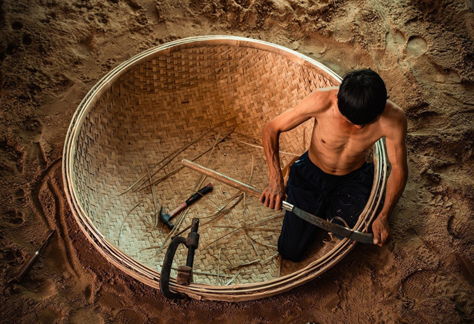 Người thợ đào hầm đất làm khuôn rồi đặt nguyên tấm mê thúng đã đan xong xuống hầm. Công đoạn lận vành là một trong những công đoạn quan trọng quyết định đến chất lượng sản phẩm để chiếc thúng sau khi lận cả vòng thúng và vành phải tròn đều, cân bằng và không biến dạng”. thung4-25725.jpg