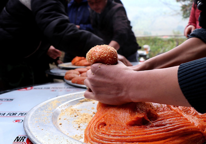 Người dân tộc Dao nắn xôi gấc xay nhuyễn trộn vừng rang để tạo hình và kích cỡ bánh giầy.