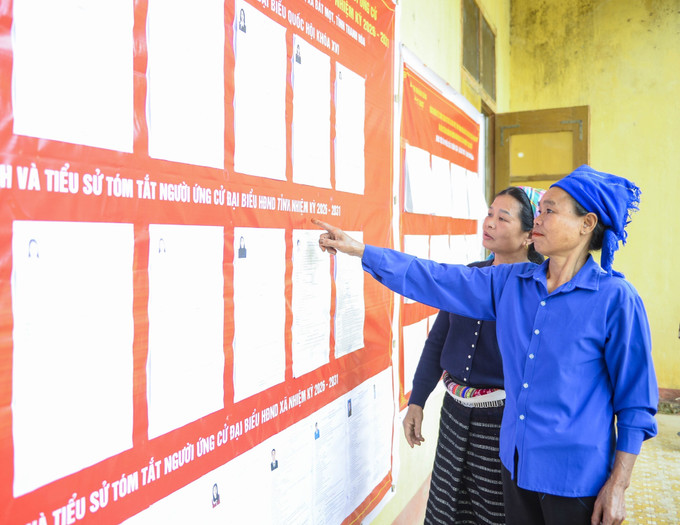 Cử tri người dân tộc thiểu số tìm hiểu thông tin về những người ứng cử. Ảnh: Hoa Mai/TTXVN