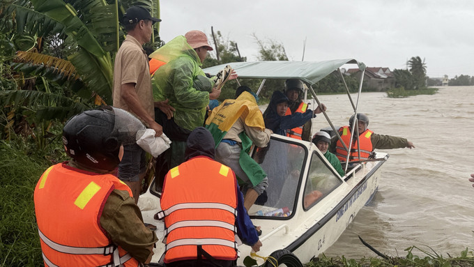 Ca nô đưa người dân vùng nguy hiểm đến nơi tránh trú mưa lũ. Ảnh: Tường Quân/TTXVN