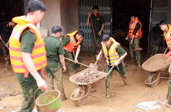 Lực lượng Công an tỉnh Lai Châu hỗ trợ người dân dọn dẹp bùn đất, khắc phục hậu quả. Ảnh: Quý Trung/TTXVN