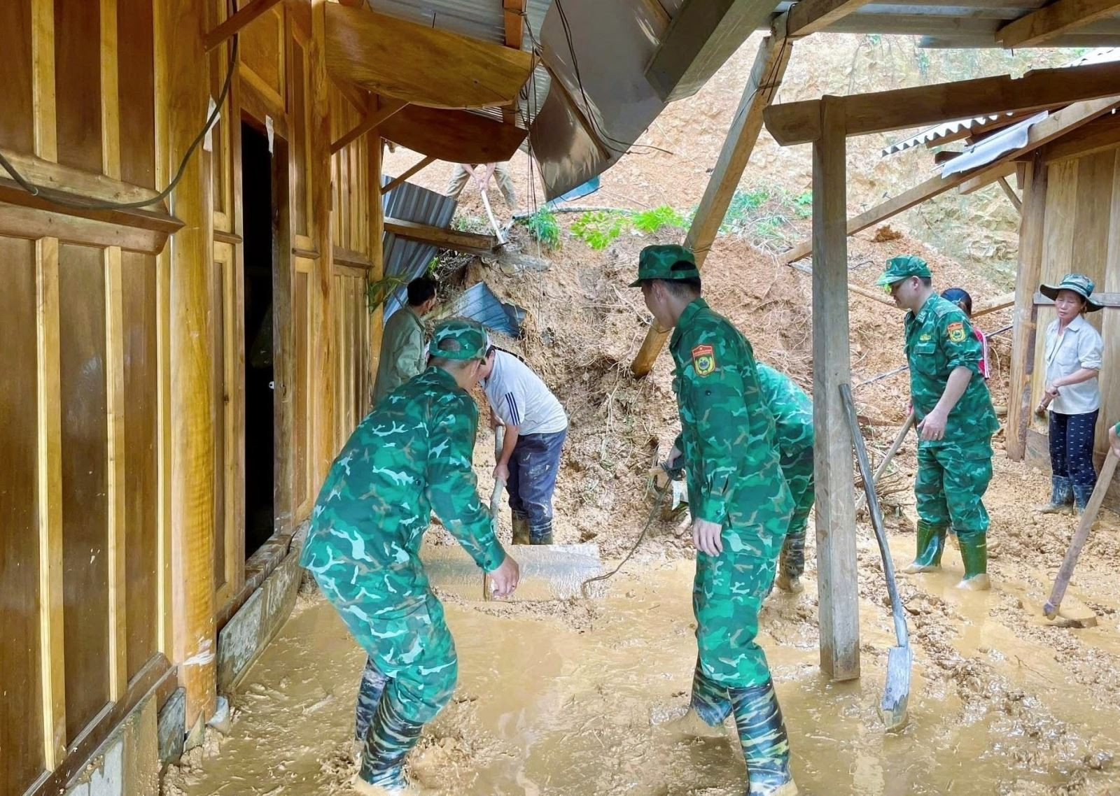 Lực lượng Bộ đội biên phòng Đồn biên phòng Mỹ Lý (Bộ đội biên phòng Nghệ An) giúp dân biên giới xã Mỹ Lý (huyện Kỳ Sơn) san gạt, di chuyển bùn đất sạt lở vào nhà dân. Ảnh: TTXVN phát Chú thích ảnh