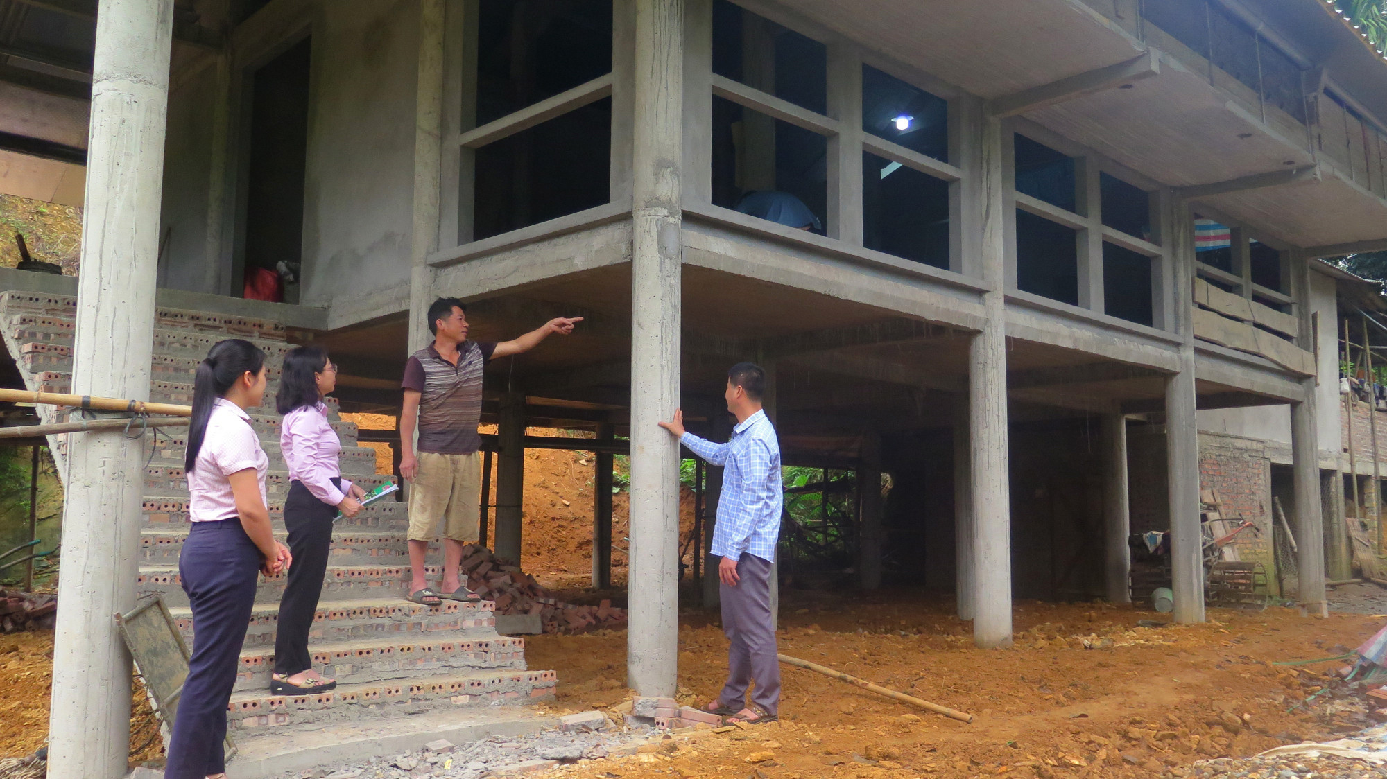 Ngôi nhà sàn bằng bê tông dần hoàn thiện của gia đình ông Quang Văn Lường (thứ 2 từ phải qua), dân tộc Tày, thôn On Cáy, xã Tân Mỹ, huyện Chiêm Hóa, tỉnh Tuyên Quang. Ảnh: Hoàng Hải/TTXVN nhasan.jpg
