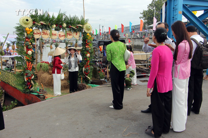 Du khách tham quan, chụp ảnh với các ghe tàu được trang trí tại điểm dừng chân Chợ nổi Cái Răng. Ảnh: Trung Kiên - TTXVN vna_potal_ngay_hoi_du_lich_van_hoa_cho_noi_cai_rang_thanh_pho_can_tho_nam_2024_7731809.jpg