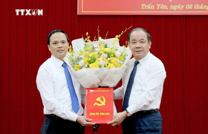 Ông Tạ Văn Long, Phó Bí thư Thường trực Tỉnh ủy trao quyết định và tặng hoa chúc mừng tân Bí thư Huyện ủy Trấn Yên Trần Anh Tuấn. Ảnh: TTXVN phát vna_potal_yen_bai_cong_bo_cac_quyet_dinh_ve_cong_tac_can_bo__7518325.jpg