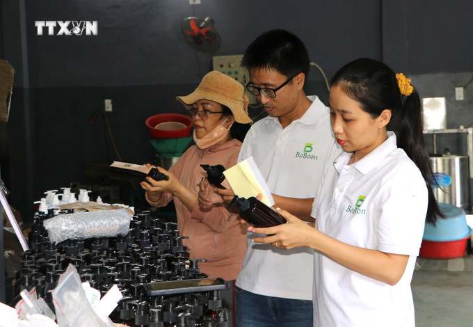 Chị Trần Thị Ngọc Cẩm kiểm tra sản phẩm dầu gội từ thiên nhiên. Ảnh: Đinh Hương - TTXVN vna_potal_phu_nu_quang_ngai_khoi_nghiep_voi_san_pham_tu_thien_nhien_7656370.jpg