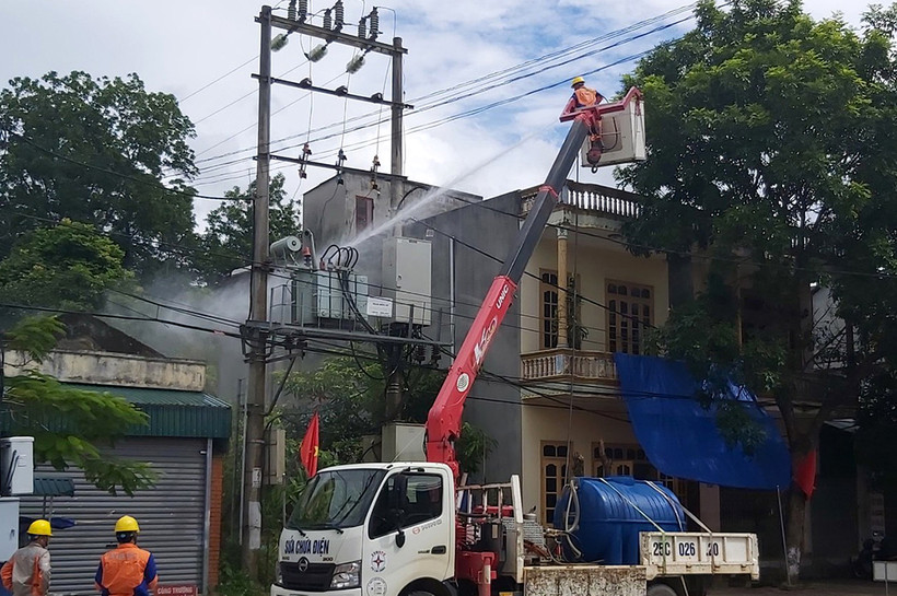 Công nhân ngành điện đang thực hiện nhiệm vụ rửa sứ bảo đảm an toàn cho hệ thống điện trên địa bàn. Ảnh: Đinh Thùy - TTXVN