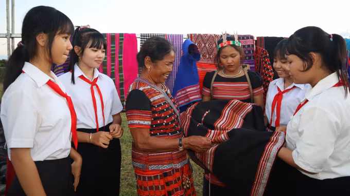Phụ nữ S'tiêng giới thiệu vải thổ cẩm truyền thống cho thế hệ trẻ tại lễ hội mừng lúa mới tại xã Tân Hưng.